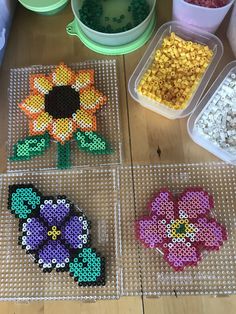 four plastic trays filled with different types of beads and flowers on top of a wooden table