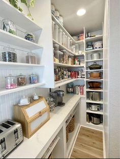 a kitchen with white cabinets and shelves filled with food