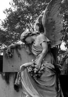 an angel sitting on top of a cement wall