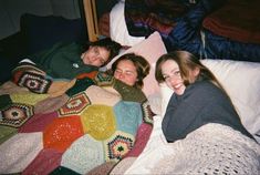 three women laying on a bed together with blankets and crocheted bedspreads