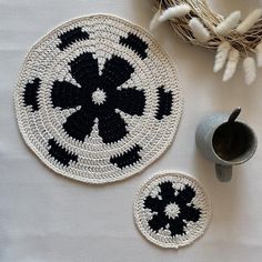 two black and white crocheted coasters next to a coffee cup on a table