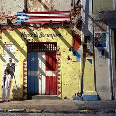 an old building painted yellow and red with a painting of a skeleton on the door