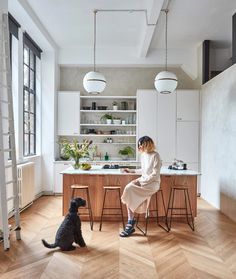 a woman sitting at a kitchen table with a dog