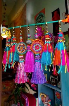 many colorful tassels hanging from a line in a room with pictures on the wall