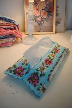 a pillow sitting on top of a white table next to a vase and some pictures