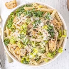 a white bowl filled with pasta and broccoli covered in parmesan cheese