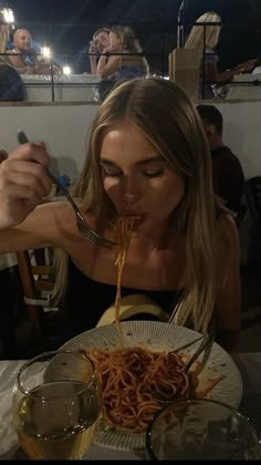 a woman is eating spaghetti at a restaurant