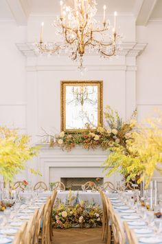 a dining room table set with flowers and place settings in front of a fire place