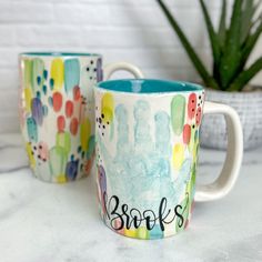 two coffee mugs sitting next to each other on top of a white countertop