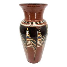 a brown and black vase sitting on top of a white table