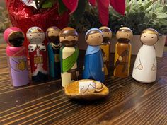 a group of wooden figurines sitting on top of a table next to a potted plant