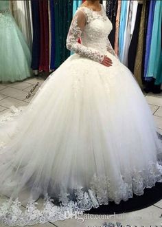 a woman in a white wedding dress standing next to a rack with dresses on it