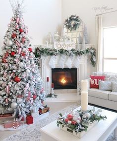 a living room decorated for christmas with white and red decorations on the fireplace mantel