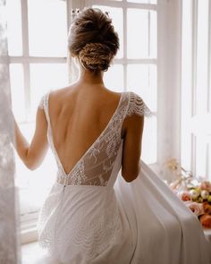 a woman in a wedding dress looking out the window