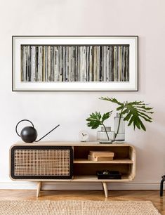 a living room with an entertainment center, plant and pictures on the wall above it