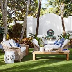 an outdoor living area with wicker furniture and palm trees in the background, surrounded by lush green grass