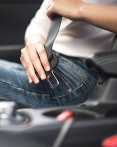 a woman sitting in the drivers seat of a car with her hand on the steering wheel