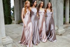 three beautiful women standing next to each other in long dresses and one is holding her hand on her hip