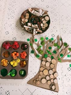 two trays filled with different types of buttons next to a tree shaped craft kit