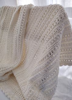 a white crocheted blanket sitting on top of a bed