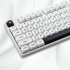 a computer keyboard sitting on top of a white table covered in white sheets and black keys