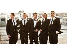 a group of men in suits standing next to each other on a bridge near the water