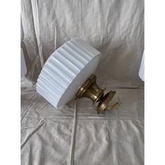 a white and gold object sitting on top of a bed next to a lamp shade