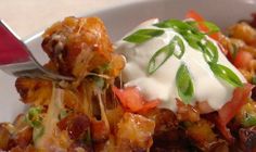 a close up of a bowl of food with a fork in it and sour cream on top