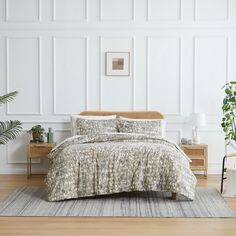 a bed in a room with white walls and wooden flooring, along with a rug on the floor