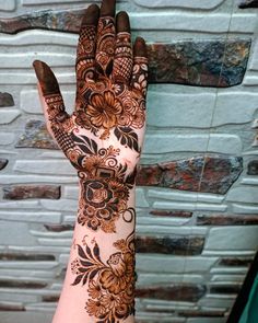 a woman's hand with henna tattoos on it and brown flowers in the middle