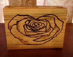 a wooden box with a drawing of a rose on the front and side, sitting on a table