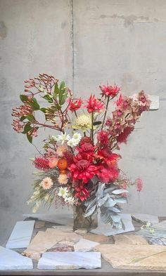 a vase filled with lots of flowers sitting on top of a table next to a wall