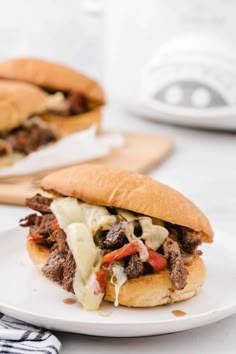 a close up of a sandwich on a plate with meat and cheese in the background