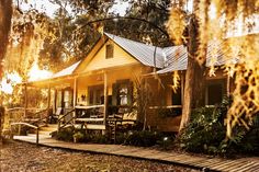 the sun shines brightly through the trees in front of a small house with picnic tables and benches