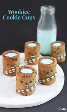 cookie cups on a white plate with blue liquid in the middle and cookies around them