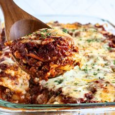 a wooden spoon scooping out some lasagna sauce from a casserole dish