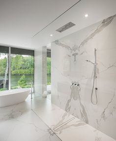 a large bathroom with marble walls and flooring next to a bathtub in front of a window