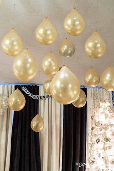 gold balloons hanging from the ceiling in front of a christmas tree