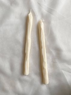 two white toothbrushes laying on top of a bed next to an ear cord