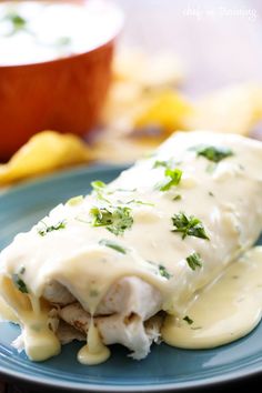 an enchilada on a blue plate with sauce and parsley