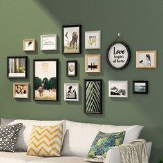 a living room filled with lots of framed pictures on the wall above a white couch