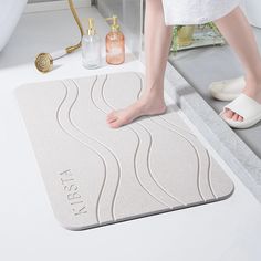 a woman is standing on the bathroom floor with her feet in the bathtub, and she's wearing white slippers