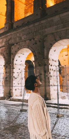 a man standing in front of an old building with arches and lights on the ceiling