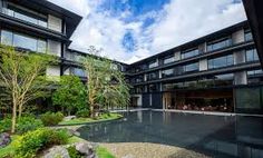 an empty pool in front of a large building with lots of windows and plants around it