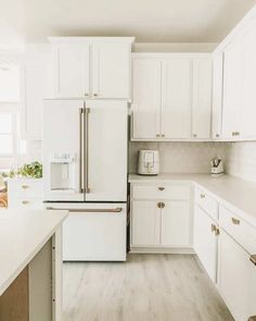 a kitchen with white cabinets and wood floors