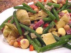 a white plate topped with green beans and other food on top of a countertop