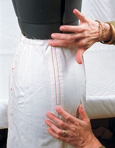 a woman is holding her stomach with both hands and touching the side of her skirt