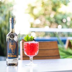 a bottle of alcohol next to a glass filled with watermelon and garnish