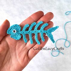 a hand holding a crocheted fish brooch