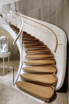 a spiral staircase made out of wooden planks and glass railing in a modern home